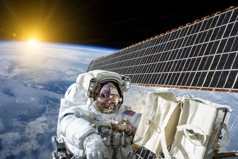 un astronauta svolge i suoi compiti mentre sullo sfondo i pannelli fotovoltaici alimenta il fabbisogno energetico dell'equipaggio
