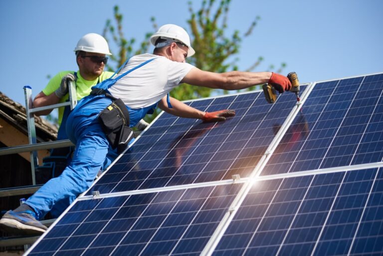 due operai installano un pannello fotovoltaico. La complessità dell'installazione incide sul costo dell'impianto