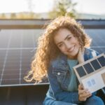 una ragazza davanti al suo impianto fotovoltaico sorride per il costo degli impianti fotovoltaici nel 2025