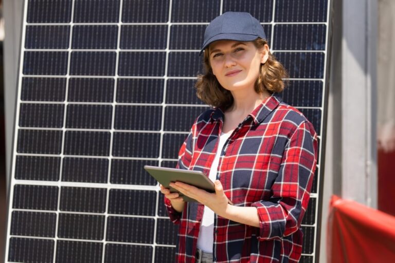 una donna ha alle spalle un pannello fotovoltaico e pensa a cosa influenza il prezzo finale del suo impianto fotovoltaico