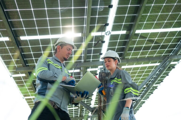 due installatori lavorano sotto le strutture di sostegno dell' impianto fotovoltaico