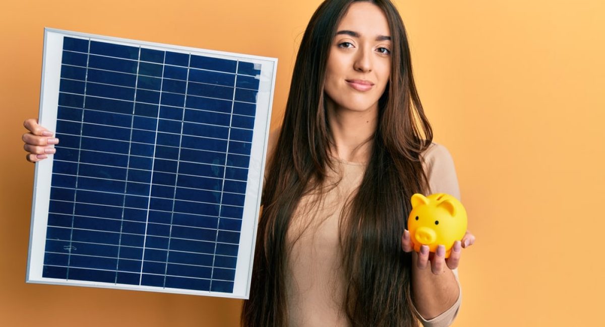 ragazza che tiene in una mano un pannello fotovoltaico e nell'altra un salvadanaio dimostra i benefici del fotovoltaico attraverso le agevolazioni fiscali