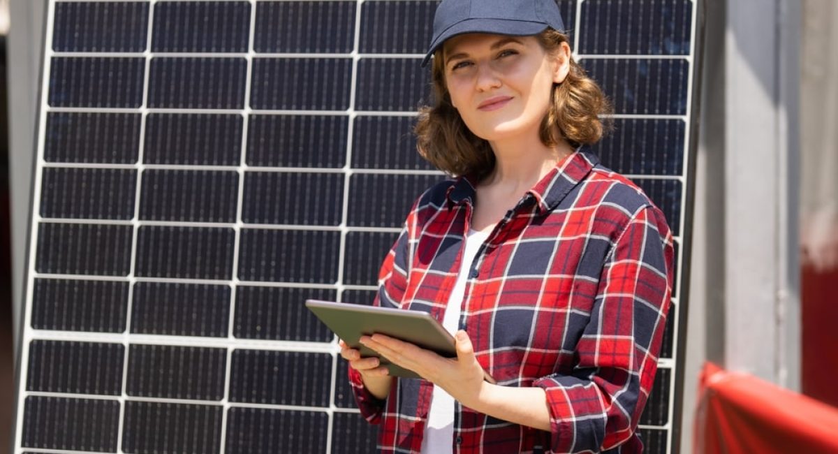 una donna ha alle spalle un pannello fotovoltaico e pensa a cosa influenza il prezzo finale del suo impianto fotovoltaico