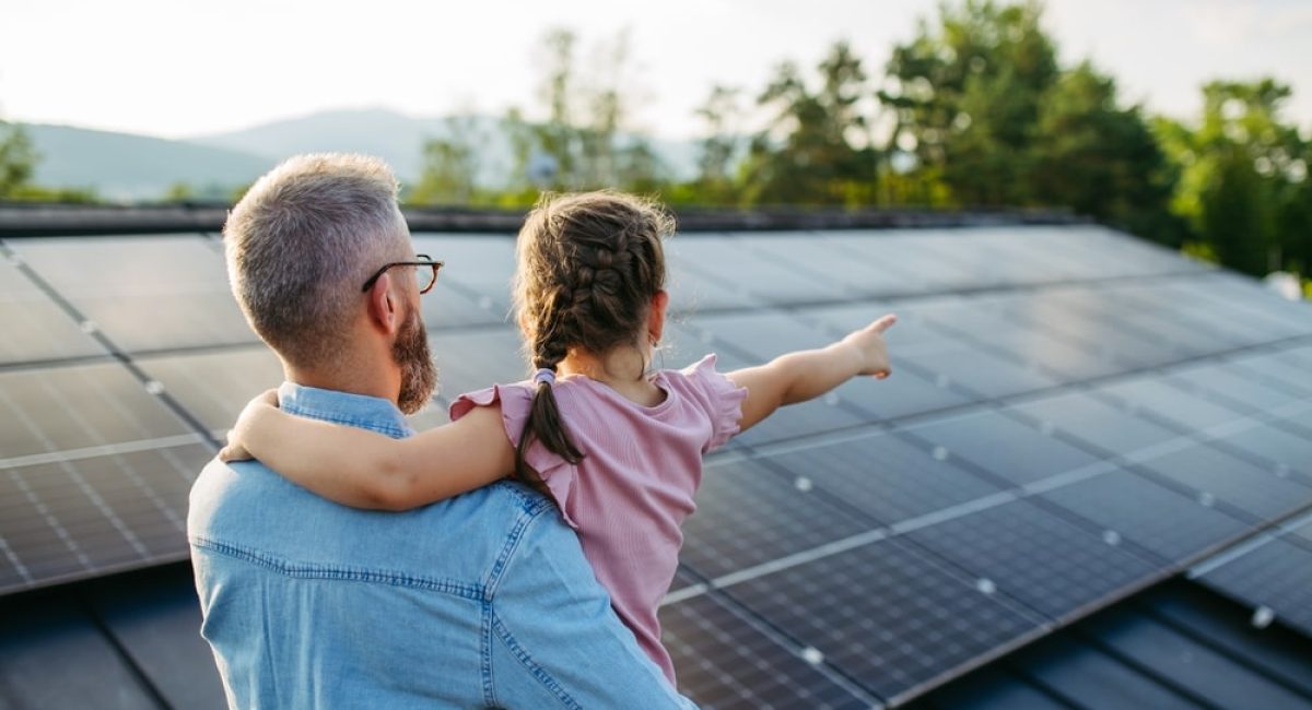 Un padre tiene la sua bambina in braccio e con lo sguardo osservano in lontananza, scrutando quali saranno i prezzi degli impianti fotovoltaici nel 2025