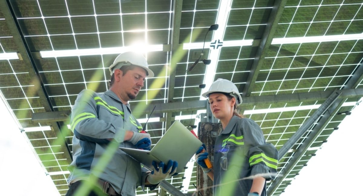 due installatori lavorano sotto le strutture di sostegno dell' impianto fotovoltaico